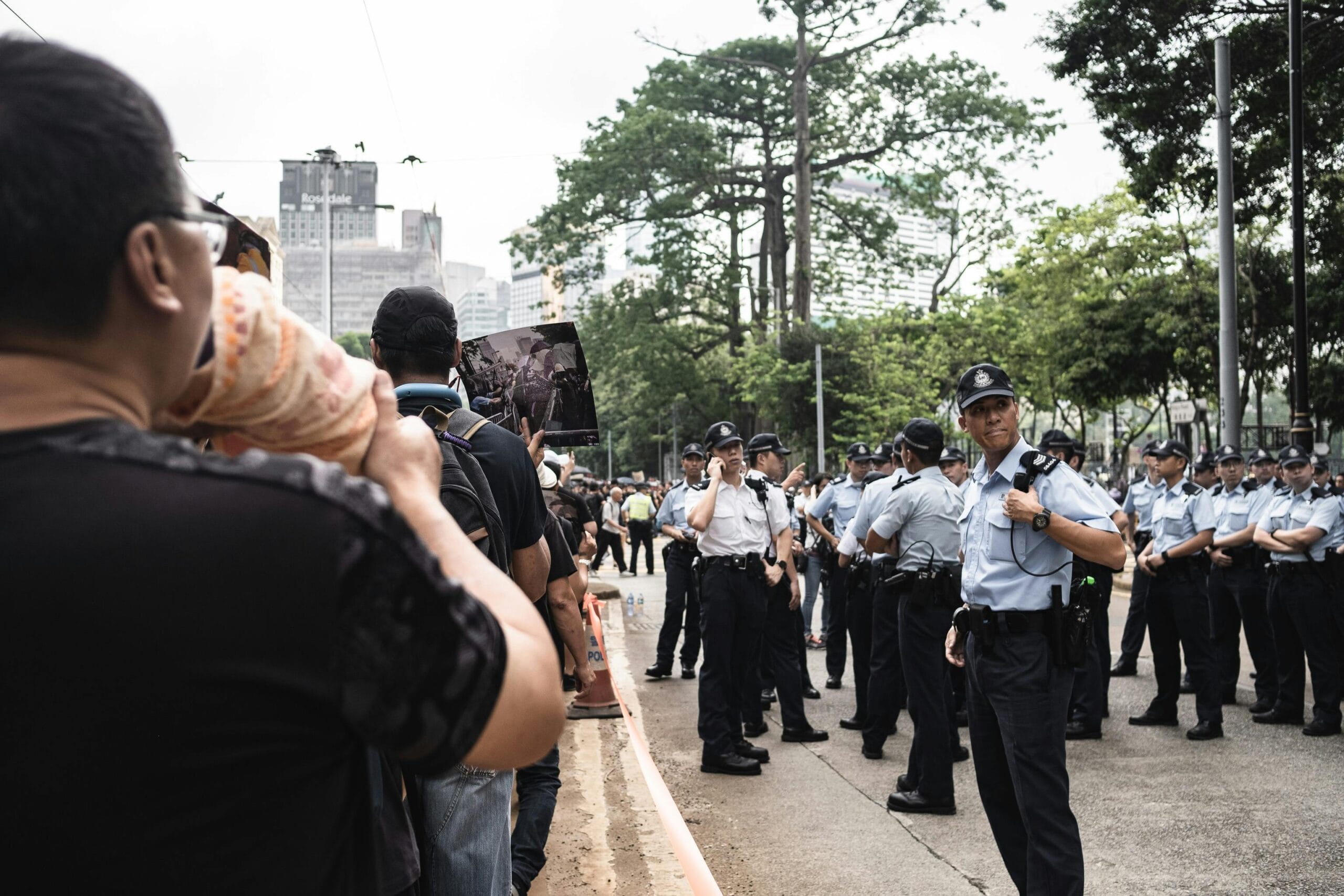 Protesters facing police officers in uniform during a public demonstration in Hong Kong city.