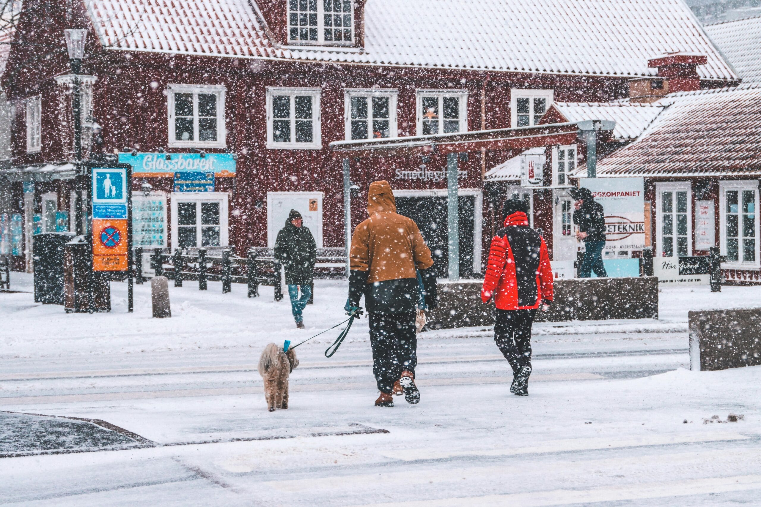 People walking in snowy Jönköping, Sweden with traditional architecture in background.